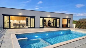 Een modern huis met een zwembad, een eethoek en een sportschool.