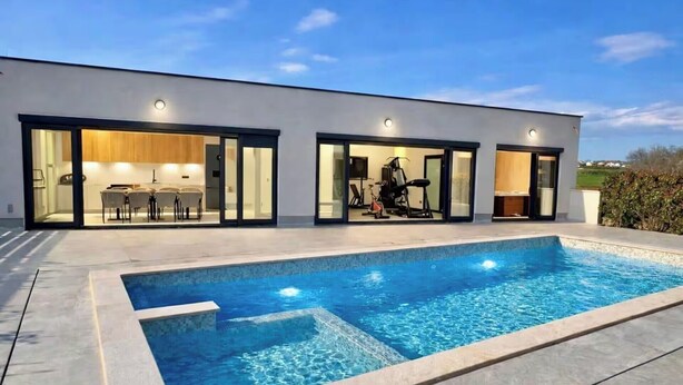 Et moderne hus med swimmingpool, spiseområde og fitnessrum.
