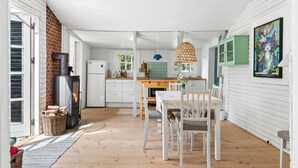 Eine gemütliche Küche mit Kamin, einem Essbereich mit Tisch und Stühlen sowie einem grünen Schrank.