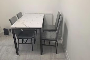 A dining table with six chairs, a radiator, and a speaker in a corner room. - House Sleeps 7 with Garden and Parking (Erith)