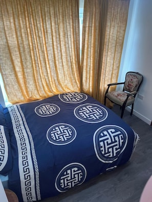 A room with a bed, a chair, and curtains.