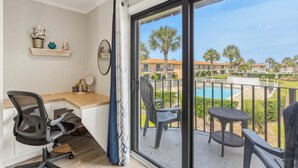 Un balcone con piscina, una scrivania con sedia e vista su una zona residenziale.