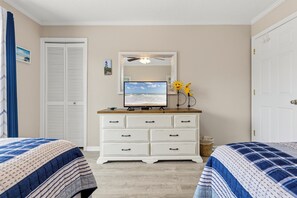 Un dormitorio con cama, cómoda, espejo, televisión y armario.