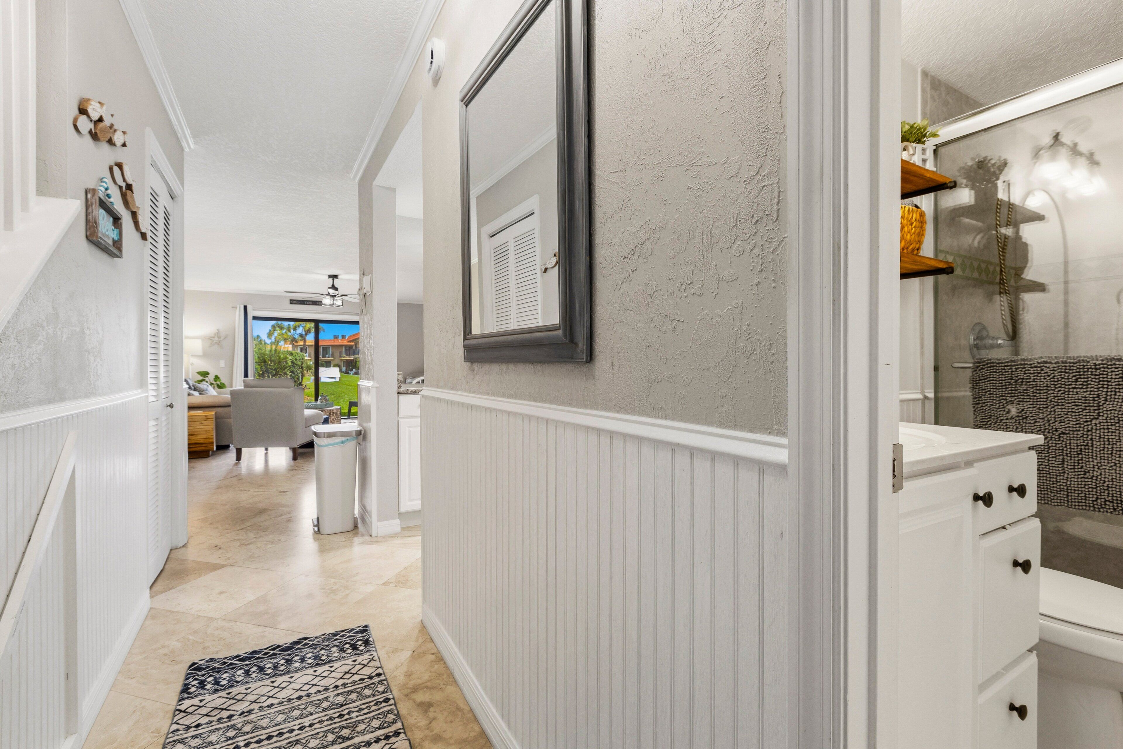 A hallway with a white radiator, a patterned rug, and a mirror on the wall.