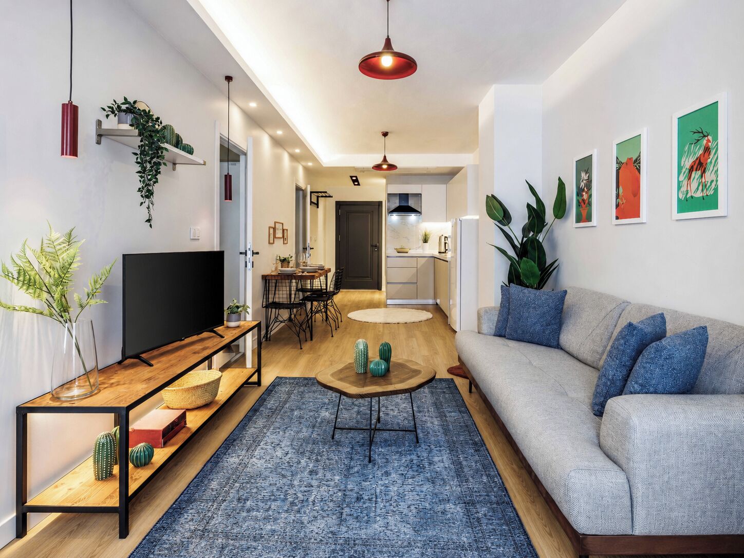 A modern living room with a sofa, coffee table, TV, and a dining area with chairs and a table.
