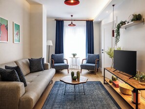 A modern living room with a sofa, two armchairs, a coffee table, a TV, and a small side table. - House Sleeps 7 with Air Conditioning (Beyoglu)