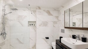 Een moderne badkamer met douche, toilet en wastafel.