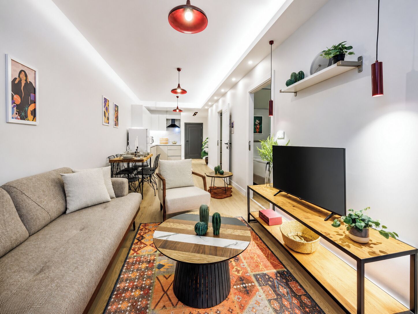 Una sala de estar moderna con un sofá, una mesa de centro, un televisor y una cocina al fondo.