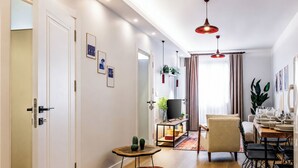 Ein modernes Wohnzimmer mit Holzboden, einem Fernsehschrank, einer Couch, einem Esstisch für sechs Personen und einem kleinen Beistelltisch mit einer Vase.