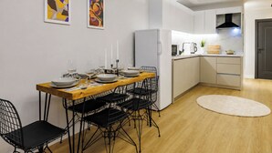 Eine moderne Küche mit weißen Schränken, einem Holztisch und schwarzen Stuhlgestellen.