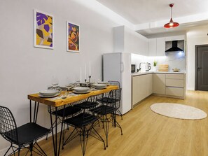 A modern kitchen with white cabinets, a wooden dining table, and black wire chairs. - Glamorous Cihangir 3 Bedrooms Apt At Monnas Suite (Beyoglu)
