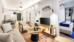 Uma sala de estar moderna com sofá, mesa de centro, televisão e área de jantar com cadeiras e mesa.