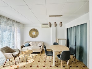 A modern living room with a sofa, a round coffee table, and a dining table with chairs. - SEVILLA.  Roses Center: Beach, Commerce and Buses one step away. WIFI. (Roses)