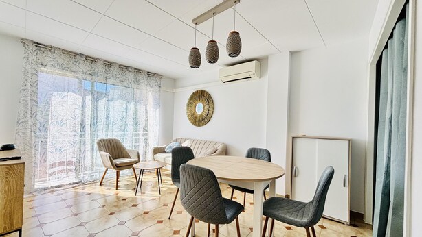 Una sala de estar moderna con una mesa redonda, cuatro sillas, un sofá y un espejo decorativo.