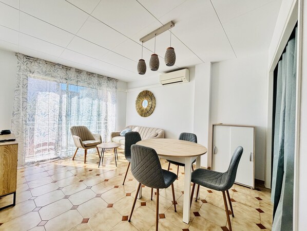 Ein modernes Wohnzimmer mit einem runden Tisch, vier Stühlen, einem Sofa und einem dekorativen Spiegel.
