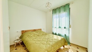 Un dormitorio con cama, mesita de noche, lámpara, ventana con cortinas y suelo de estampado geométrico.