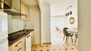 Una cocina moderna con horno integrado, lavavajillas y comedor con mesa y sillas.