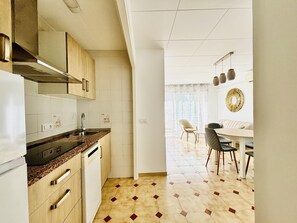 Eine moderne Küche mit Einbauofen, Geschirrspüler und einem Essbereich mit Tisch und Stühlen.