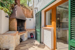 A brick-built outdoor kitchen with a chimney, a stone wall, and a wooden door. - Completely renovated house with pool and sea views in Aiguablava (Begur)