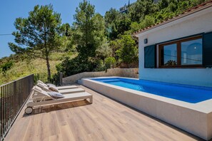 A modern outdoor pool area with lounge chairs and a stone wall. - Completely renovated house with pool and sea views in Aiguablava (Begur)