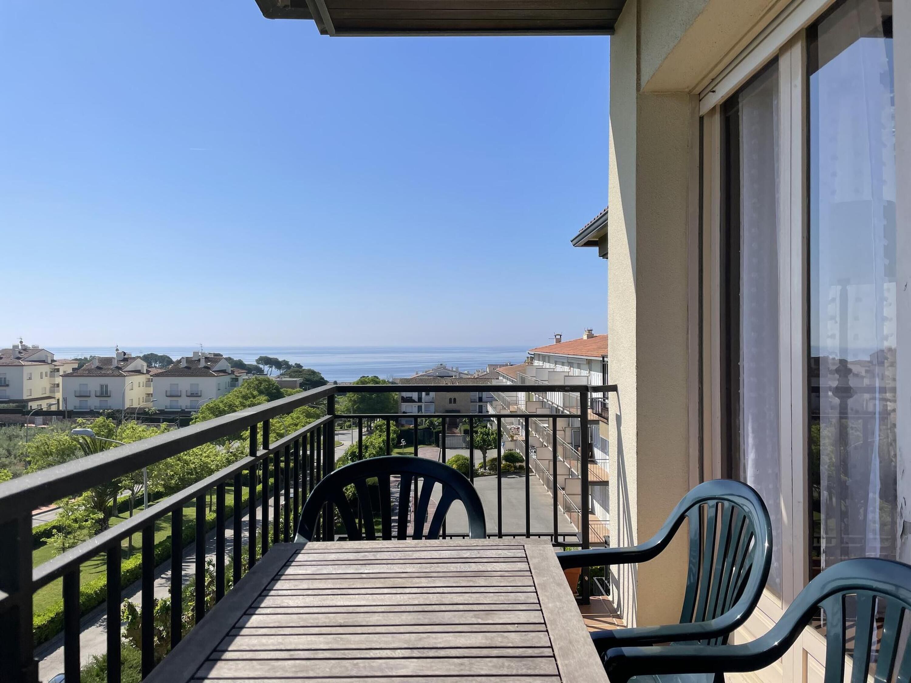Ein Balkon mit Meerblick, einem Holztisch und zwei Stühlen.
