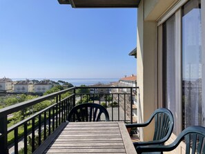 A balcony with a view of the sea, a wooden table, and two chairs. - AJ-17 Apartment near the center, large community with pool (Calella de Palafrugell)