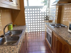 A kitchen with a stainless steel sink, a stove, and a microwave. - AJ-17 Apartment near the center, large community with pool (Calella de Palafrugell)