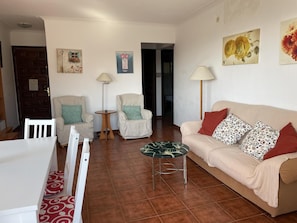 Un salon comprenant un canapé, deux fauteuils, une petite table ronde et une lampe.
