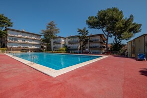 A swimming pool with a red deck, surrounded by multi-story buildings with balconies. - AJ-21 Beautiful apartment near the center with swimming pool (Calella de Palafrugell)