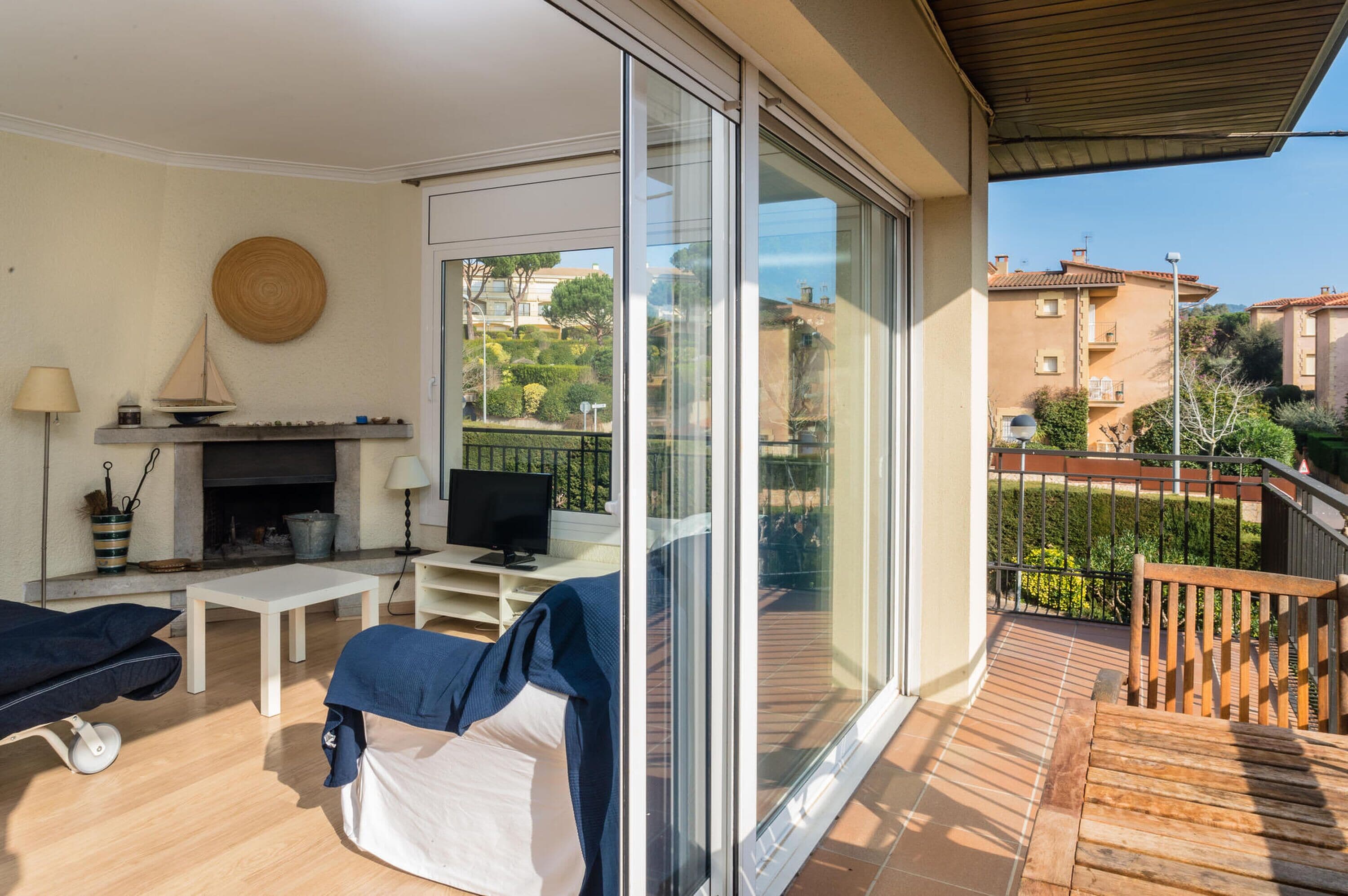 A balcony with a wooden floor, a sofa, a table, and a television.