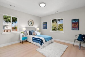 Ein Schlafzimmer mit einem Bett, Nachttischen, einem flauschigen Teppich und motivierenden Postern an der Wand.