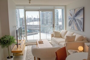A modern living room with a sofa, coffee table, and a potted plant. - Luxury 28th-Floor Downtown Haven, Skyline Views, Five-Star Amenities & Location (Vancouver)