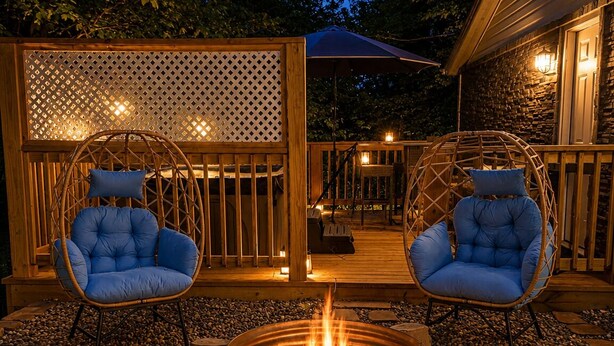 Un espacio al aire libre con dos sillones de mimbre, un pozo de fuego y una terraza de madera.