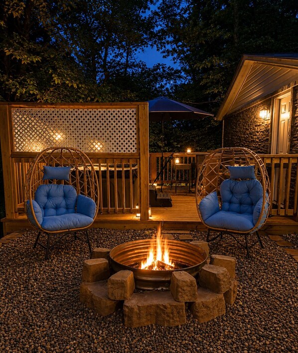 Un espace extérieur aménagé avec deux fauteuils en osier, un foyer et une terrasse en bois.