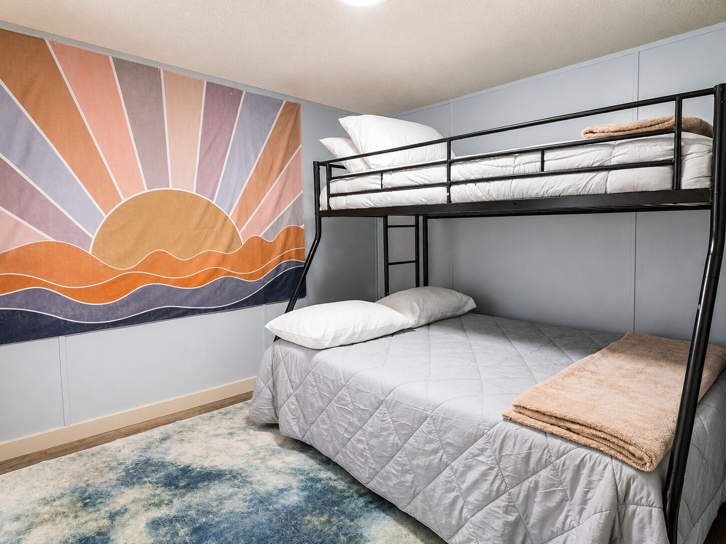 Une chambre avec un lit superposé, une fresque murale, une couvre-lit matelassée et un tapis moelleux.