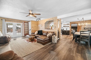 Ein geräumiges Wohnzimmer mit einer Ledersofa, einer Essecke mit Holztisch und -stühlen sowie einer Küchenzeile mit modernen Geräten.