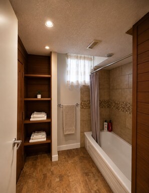 A bathroom with a wooden vanity, a shower with a glass door, and a towel rack.