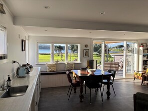 A kitchen with a view of the outdoors, a dining area with chairs, a table, and a view of the landscape.