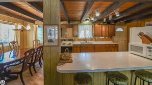 Une cuisine rustique avec des meubles en bois, une table à manger et des tabourets de bar.