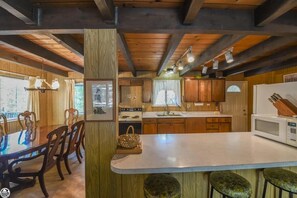 Une cuisine rustique avec des meubles en bois, une table à manger et des tabourets de bar.