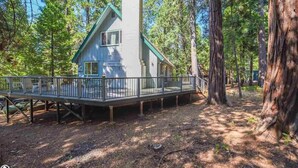 Une cabane dotée d’une terrasse, entourée d’arbres.