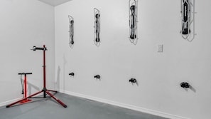 Una habitación con una bicicleta estática roja, equipo de ejercicio instalado en la pared y una pared blanca.