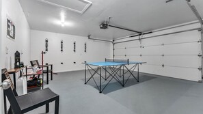 Een kamer met een tafeltennistafel, een bureau en een stoel.