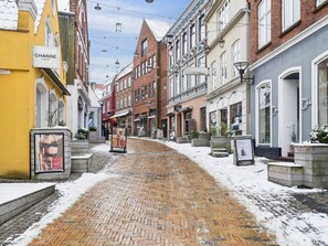 Una calle adoquinada flanqueada por edificios históricos, algunos con letreros que indican comercios.