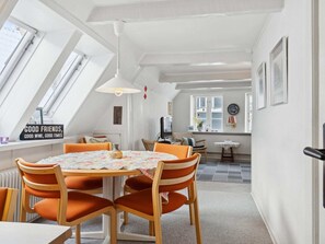 A cozy room with a round table, orange chairs, a ceiling fan, and a view of the city through large windows. - 4 Star Holiday Home in Aabenraa (Aabenraa)
