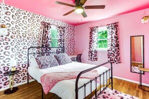 Ein Schlafzimmer mit Bett, Deckenventilator und fensterbepflanzten Fenstern.