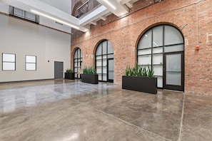 Un hall espacioso con suelo de concreto pulido, amplias ventanas de arco y paredes de ladrillo.
