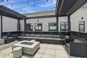 Un espacio al aire libre con una chimenea, sillones de descanso y una pérgola.
