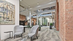 A spacious lobby with high ceilings, exposed brick walls, and a modern seating area.