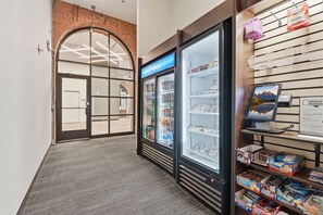 Un pasillo con un arco de ladrillo, un refrigerador Pepsi y una exhibición de aperitivos.